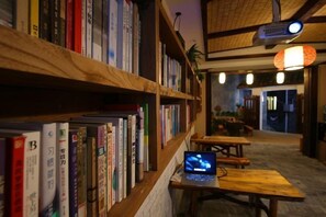 Eine Bibliothek mit Bücherregalen, einem Laptop auf einem Tisch und einer Holzbalkendecke.