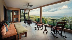 Un balcón con sofá, sillas y una mesa, con vistas a un paisaje pintoresco.