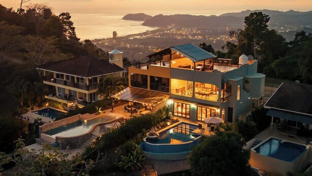 Una casa de varios pisos con piscina, mobiliario exterior y vista al océano.