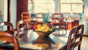 Una mesa de comedor con un frutero en el centro, rodeada de sillas de madera.