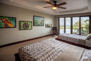 A bedroom with two beds, a ceiling fan, and a large window with a view.