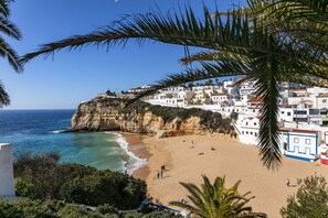 A coastal town with a beach, white buildings, and a cliff overlooking the sea.