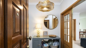 A hallway with a wooden door, a grey console table with a lamp, a mirror, and baskets of items.