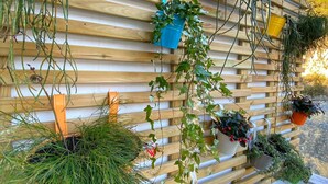 A wooden slatted wall with various potted plants hanging from it.