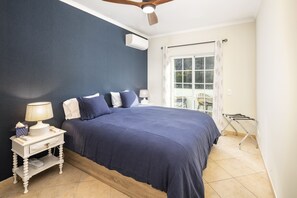 A bedroom with a bed, bedside table, lamp, and a window with curtains.