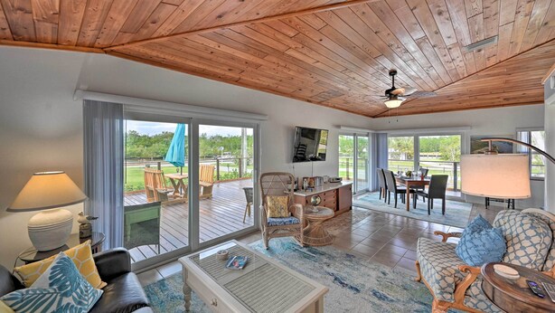 A spacious living area with a wooden ceiling, large windows, and a view of the outdoors. - Everglades Getaway w/ Deck & Water Views! (Everglades City)