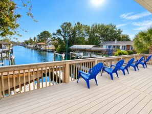 A deck with blue chairs overlooking a marina with boats.