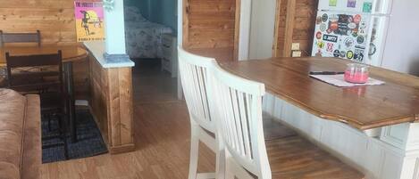 A cozy kitchen with wooden cabinets, a white refrigerator, and a dining area with a wooden table and white chairs.