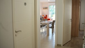 A modern interior with a dining area, a kitchen, and a wooden door. - Beautiful apartment 50m from the marina (Saint-Valery-sur-Somme)