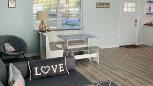 Een moderne woonkamer met een grijze bank, een klein wit tafeltje en een plafondventilator.
