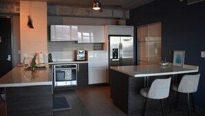 A modern kitchen with a central island, stainless steel appliances, and bar stools. - Modern Condo at Atlantis (San Juan)