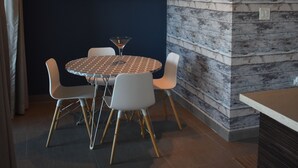 A modern dining area with a round table, white chairs, and a dark wall with a textured accent wall. - Modern Condo at Atlantis (San Juan)