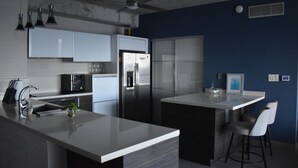 A modern kitchen with stainless steel appliances, a central island, and bar stools. - Modern Condo at Atlantis (San Juan)