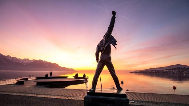 Une statue sur une jetée, avec un coucher de soleil en arrière-plan.