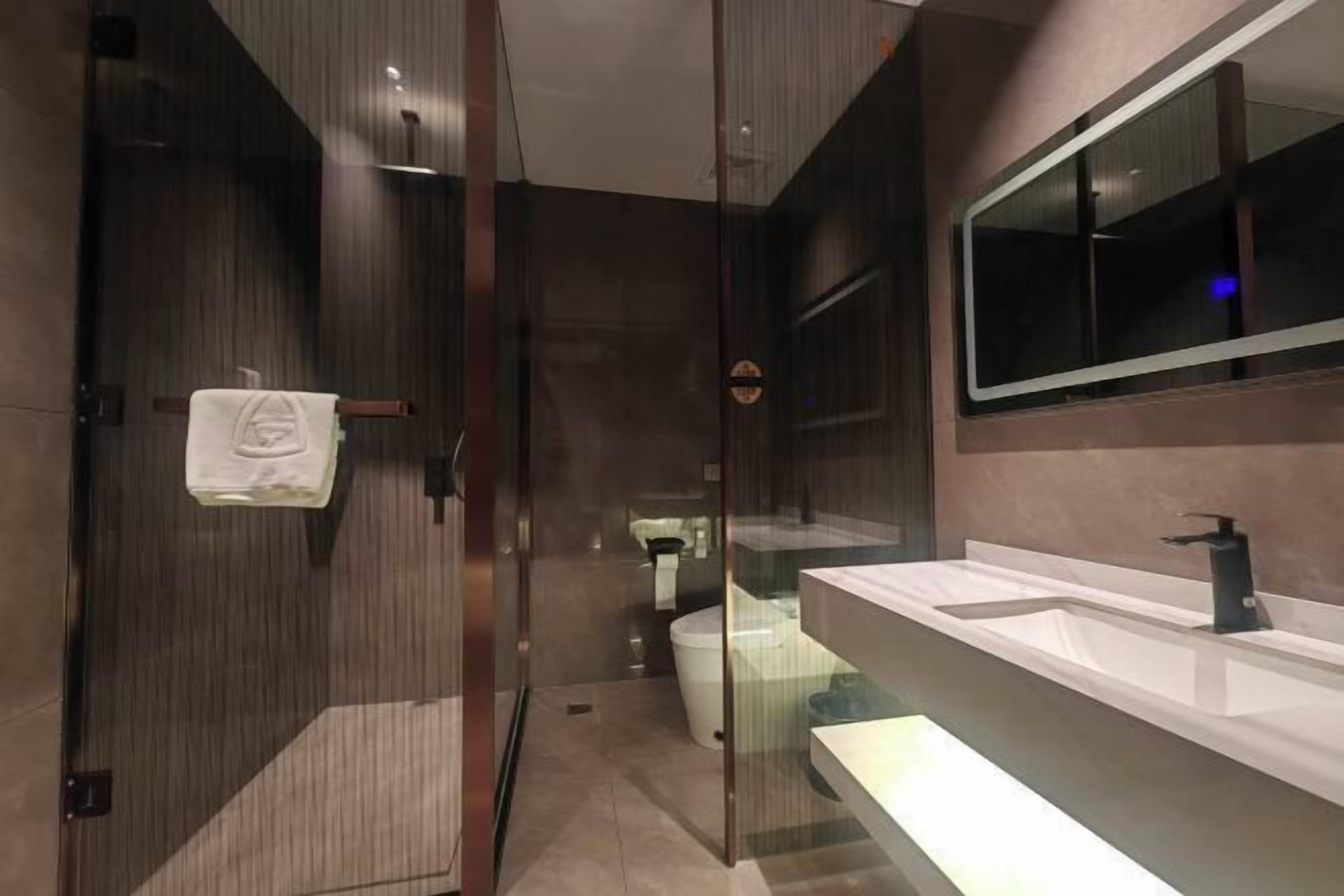 A modern bathroom with a glass shower enclosure, a large mirror, and a dual sink vanity.