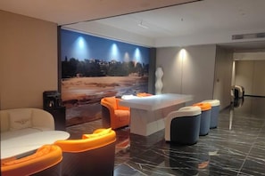 Un hall d’hôtel moderne comprenant un comptoir d’accueil, un espace salon et une grande fresque murale.