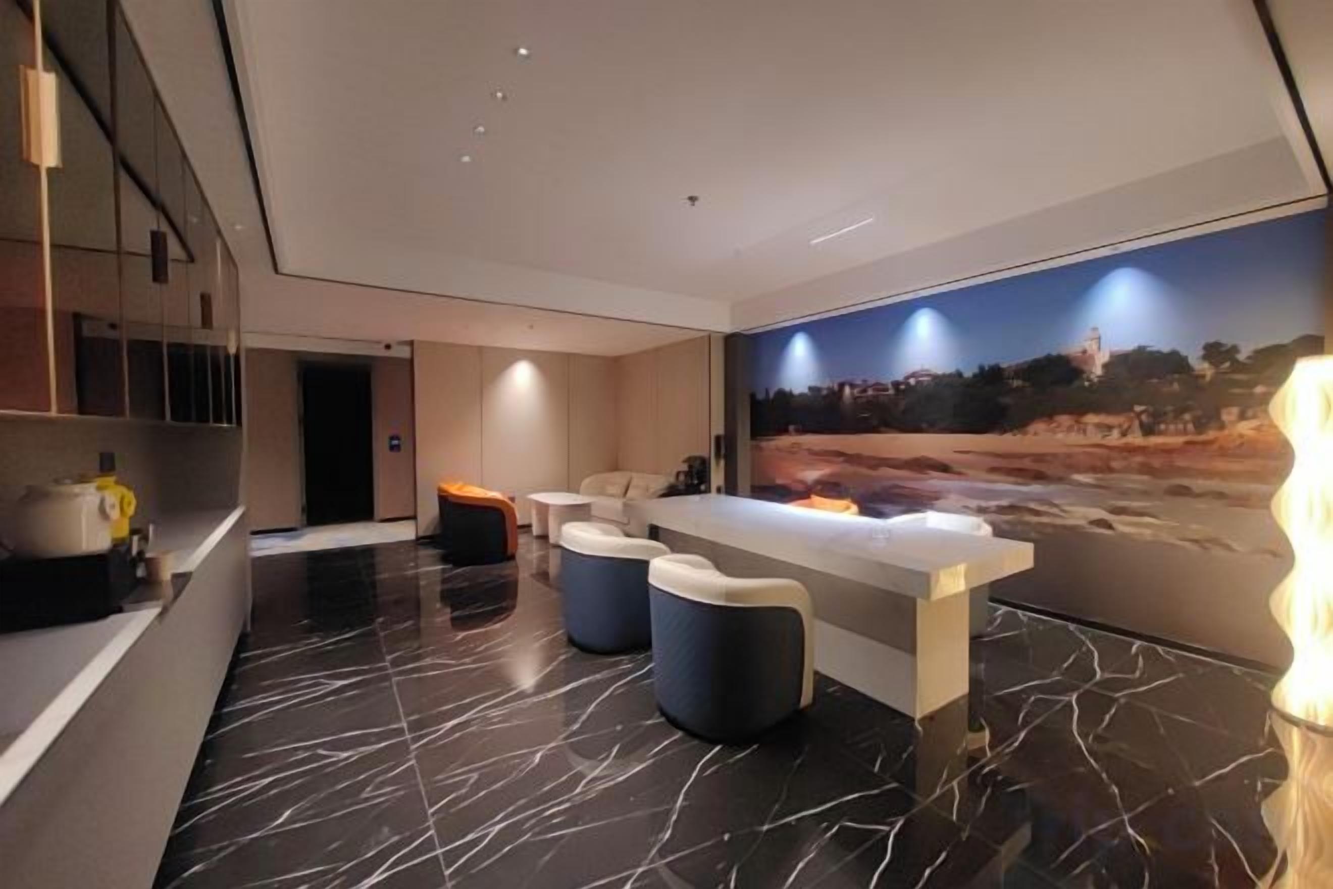 Um lobby de hotel moderno com balcão de recepção, área de estar e um grande mural na parede.