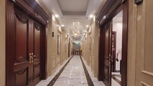 Un pasillo largo y estrecho con suelo de mármol y puertas de madera a ambos lados.
