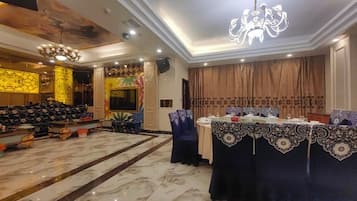 A banquet hall with a chandelier, a stage, and a long table set for a formal event.