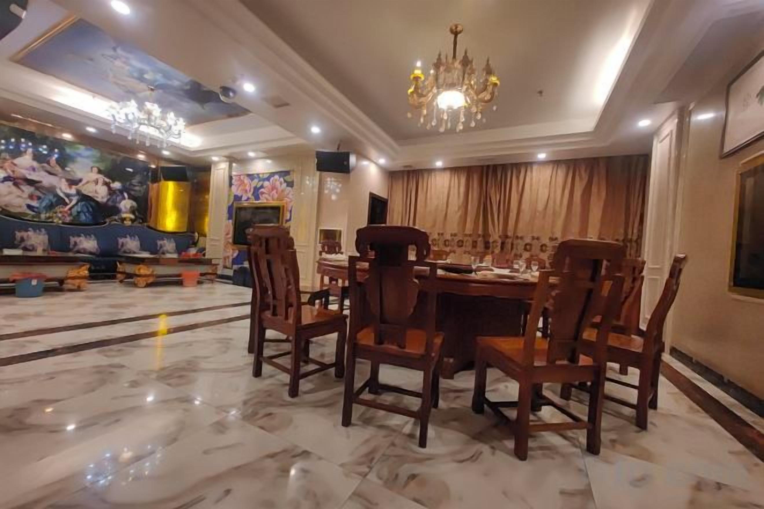 A dining area with a marble floor, wooden chairs, a chandelier, and a large painting on the wall.