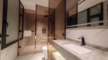 Un baño moderno con cabina de ducha de vidrio, un lavamanos grande y un espejo.