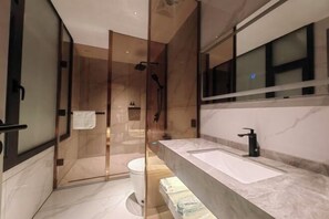 Une salle de bain moderne avec une douche à parois de verre, un grand lavabo et un miroir.