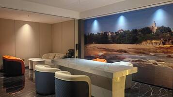 Un moderno vestíbulo de hotel con un mostrador de recepción de mármol, zona de estar y un gran mural decorativo en la pared.