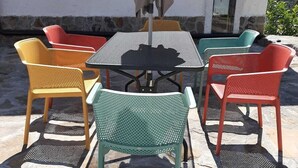 Een terras buiten met een tafel en stoelen, een kleine tafellamp en een wandairconditioner.
