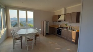 Een moderne keuken met een eetgedeelte, grote ramen en uitzicht op het platteland.