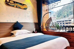 Ein Hotelzimmer mit Bett, Fenster mit Blick auf Gebäude und einer dekorativen Wandgestaltung.