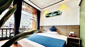 Habitación de hotel con cama, mesita de noche, una obra de arte en la pared y vistas a través de la ventana.