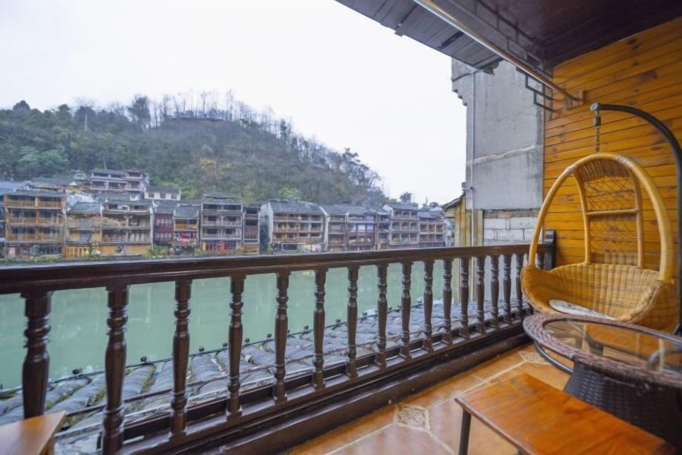 Un balcón con barandilla de madera que da a un río y edificios tradicionales.