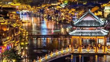 Une ville chinoise traditionnelle construite sur l’eau, avec des bâtiments illuminés et un pont.