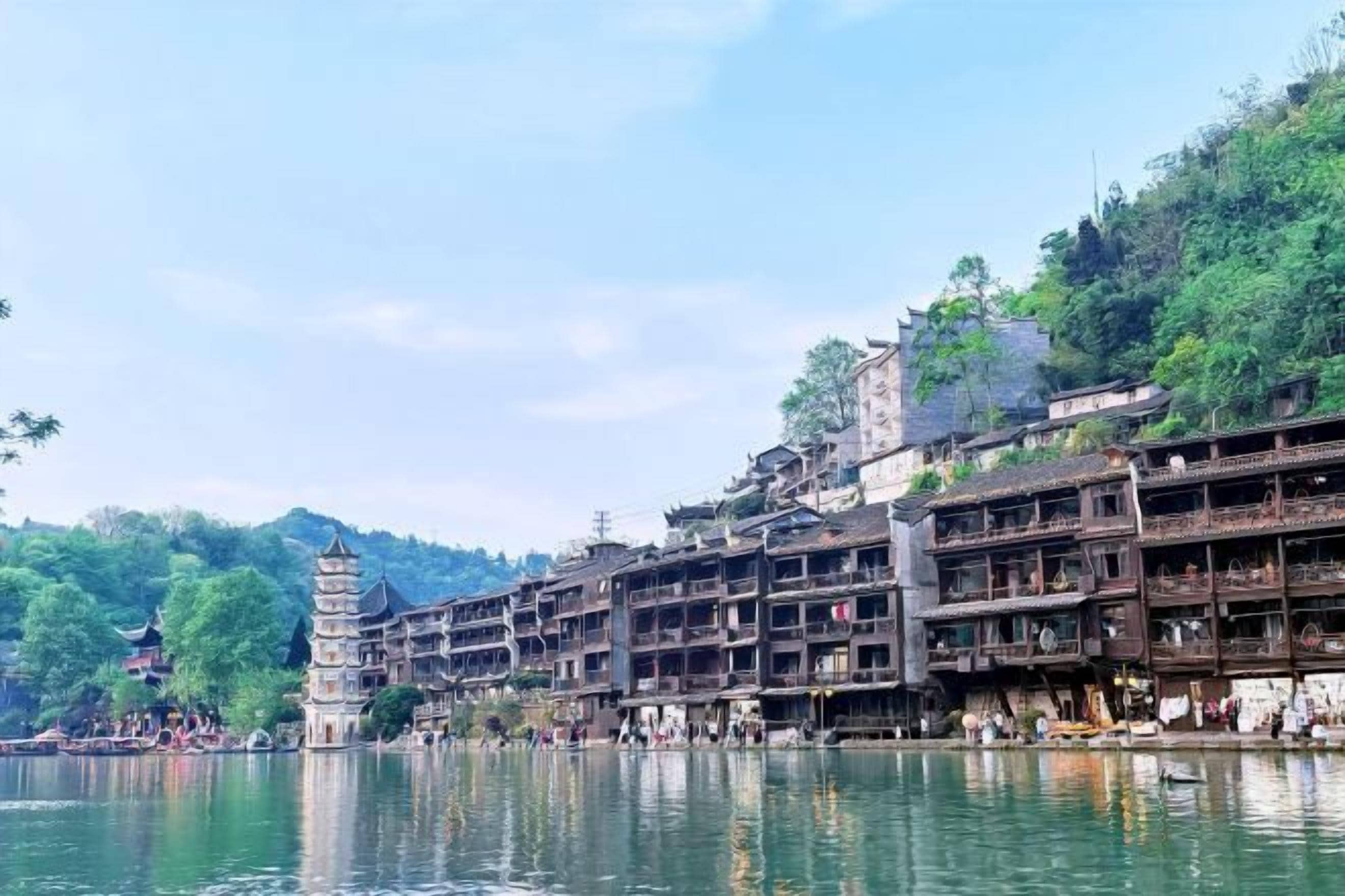 A riverside town with traditional architecture, including multi-story buildings and a pagoda.