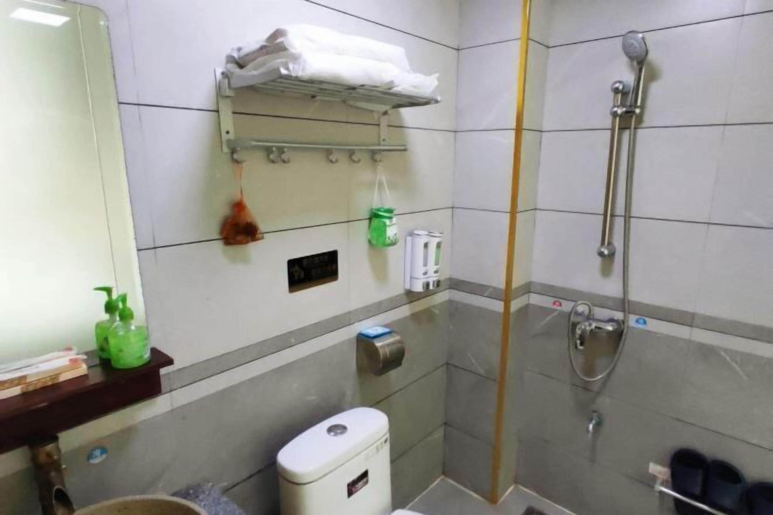 Une petite salle de bain comprenant des toilettes, un lavabo, une douche et un porte-serviettes.