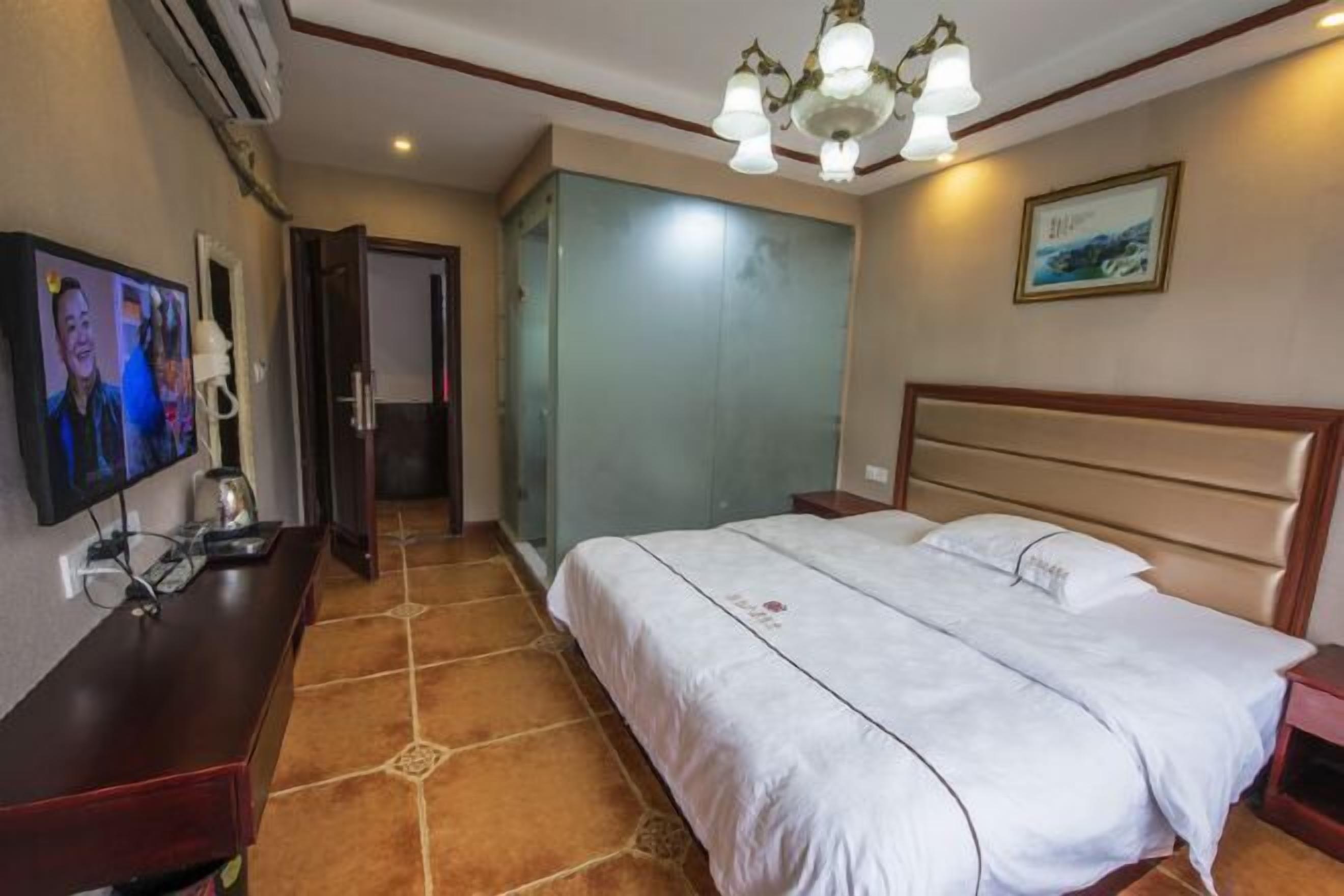 A hotel room with a bed, a TV, a desk, and a bathroom door.