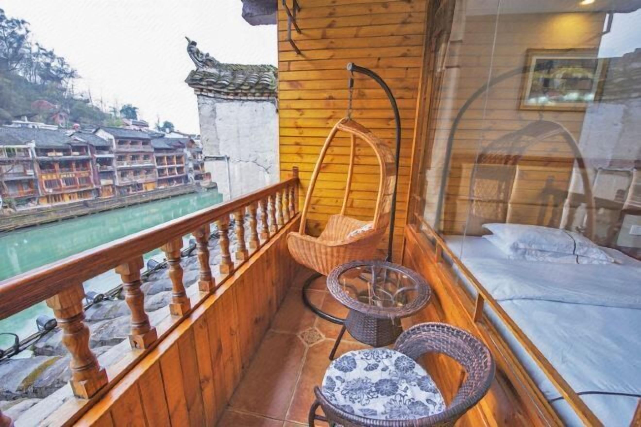 A balcony with wicker furniture, a hanging chair, and a bed.
