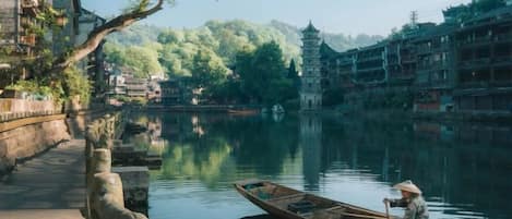 Un edificio tradicional con techo al estilo pagoda, un río tranquilo y una persona en una barca.