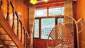 Un interior de madera con una escalera, un sillón colgante y una ventana con vistas.