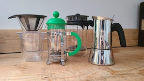 Un plan de travail de cuisine équipé de divers appareils pour préparer le café, notamment une cafetière à piston, une machine à café filtre et un moulin à café.