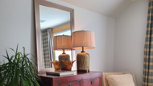 Une commode en bois avec un miroir, une lampe et une chaise.