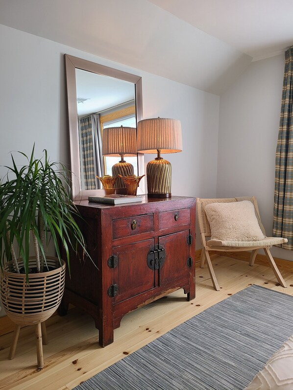 Une commode en bois avec un miroir, une lampe et une chaise.