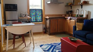 Un espace de vie compact comprenant un coin cuisine, un coin repas et un espace détente avec un canapé et un fauteuil rouge.