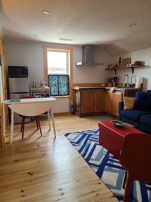 Un espace de vie compact comprenant un coin cuisine, un coin repas et un espace détente avec un canapé et un fauteuil rouge.