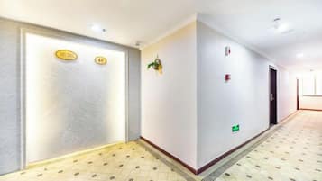 Ein Hotelgang mit einem gemusterten Boden, einem Empfangstresen mit einer Schilderung und einer Tür mit einer Nummer.'