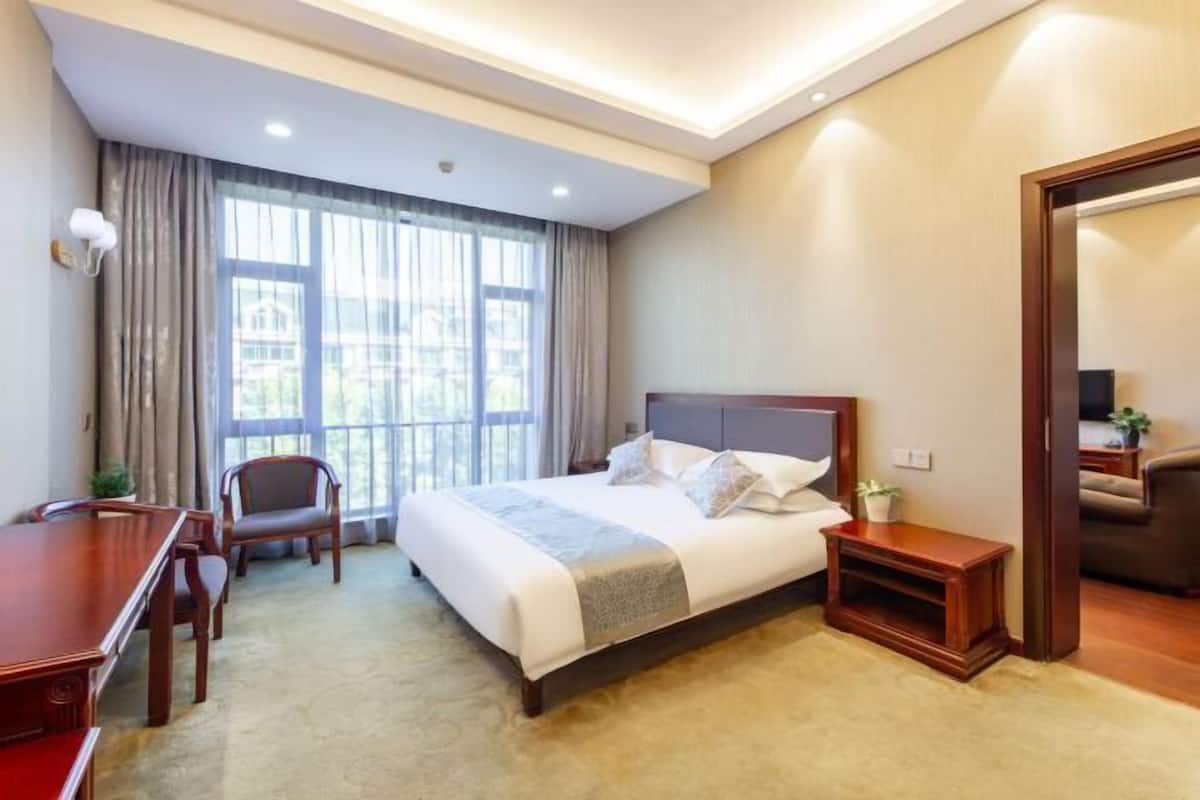 Une chambre d’hôtel avec un grand lit, un bureau, une chaise et une petite table.
