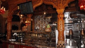 Eine Bar mit aufwendiger Holzvertäfelung, einer Fliesenrückwand und Edelstahlgeräten.