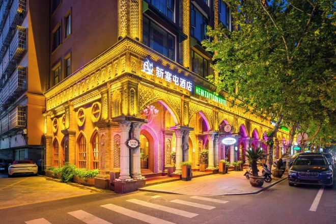 La façade d’un hôtel, avec une enseigne lumineuse et un passage piéton.