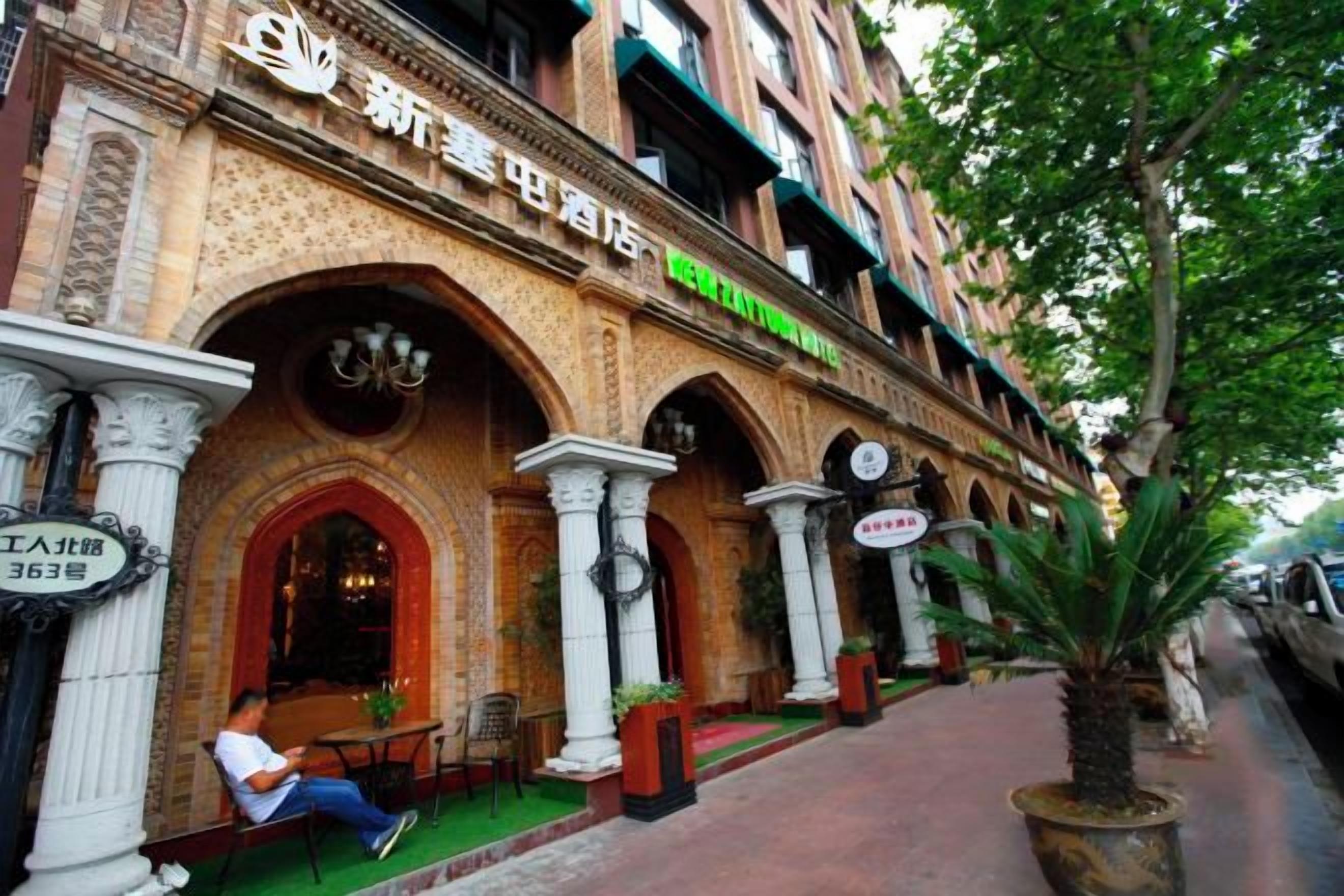 Un edificio con entradas arqueadas y un cartel que indica un hotel.