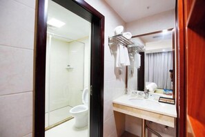 Une salle de bain avec une paroi en verre, des toilettes, un lavabo et un porte-serviettes.